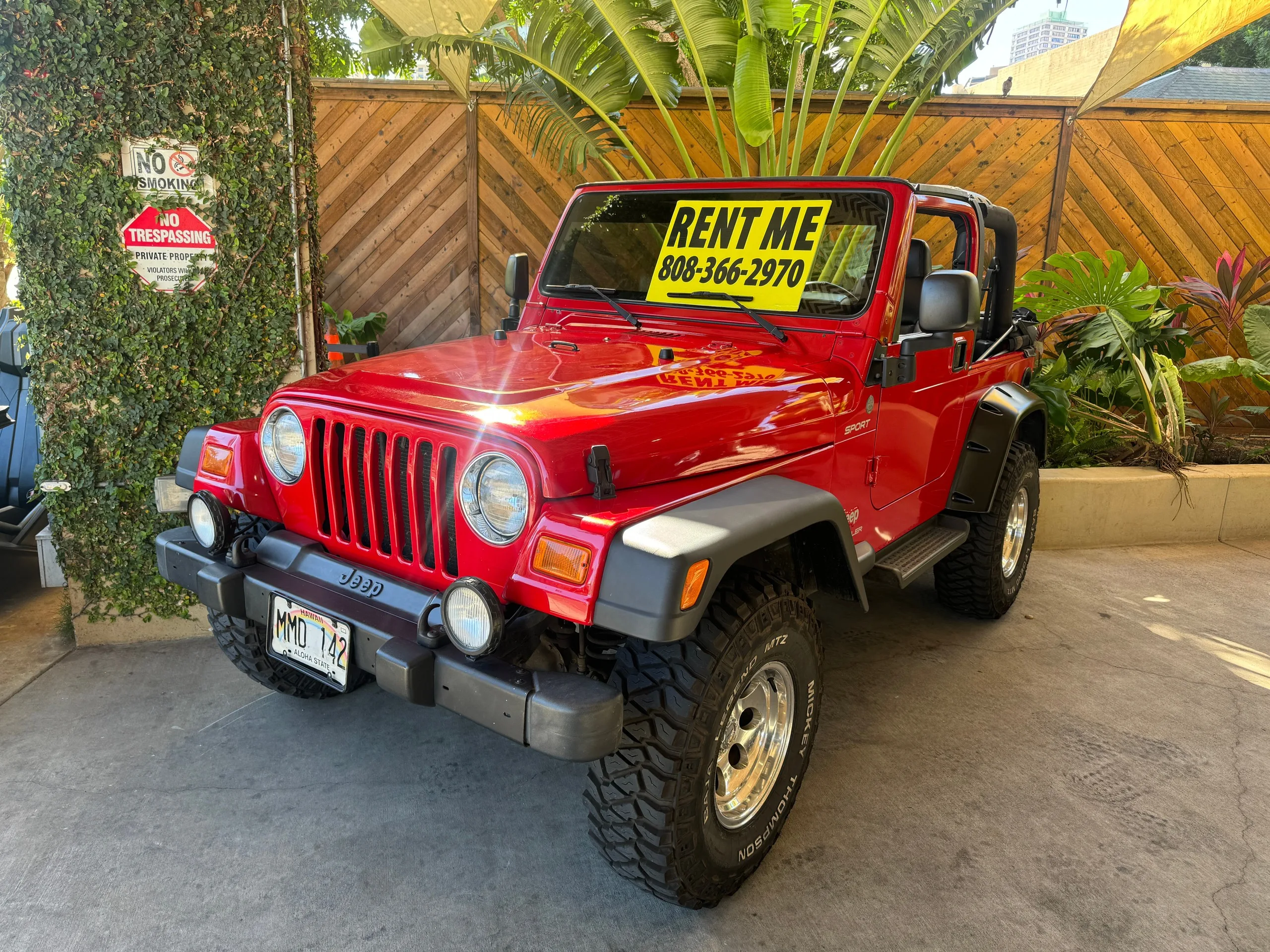 Bright red vintage Jeep parked for rental in Waikiki