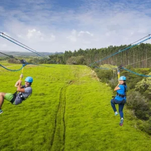 Zipline riders crossing over tall waterfalls
