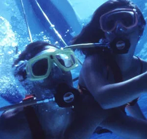 Person wearing SNUBA gear preparing to dive underwater