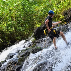 Person rappelling down waterfall cliff