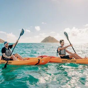 Kayaker paddling toward Mokulua Islands in bright sunlight